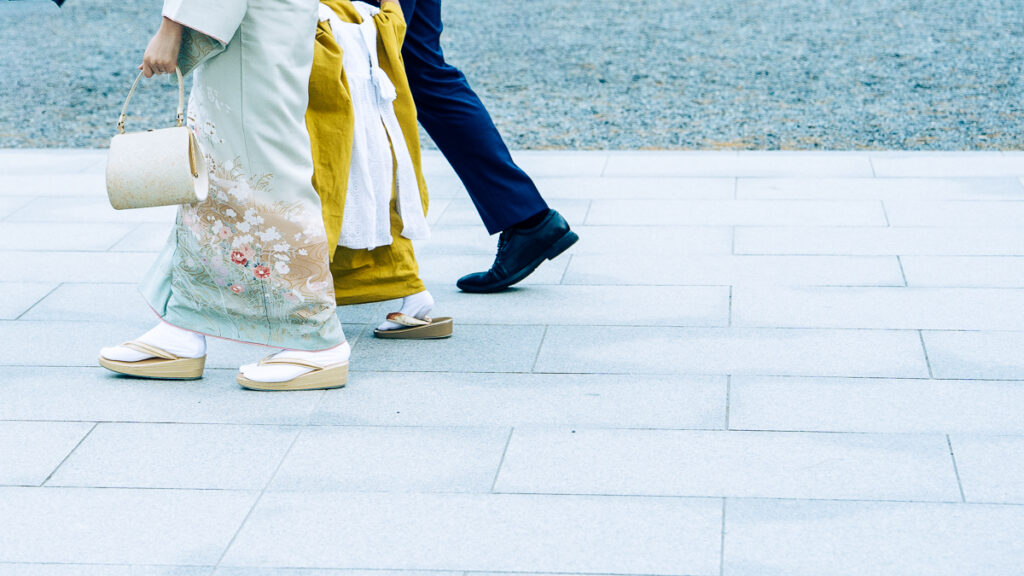 A family walking after a ceremony showing traditional kimono and sandals against the gravel courtyard at Hokkaido-Jingu