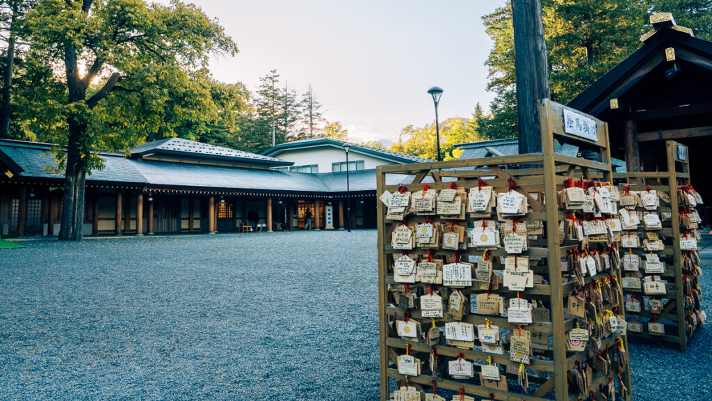 Wooden ema plaques with handwritten prayers hang on a wooden rack in the courtyard of Hokkaido-Jingu in Sapporo
