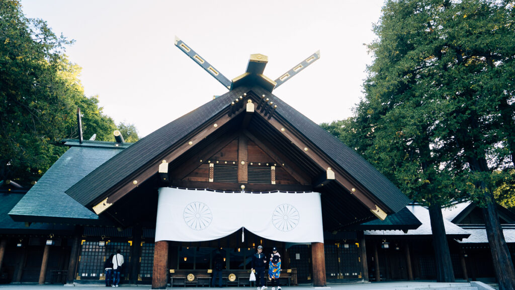 The main building of Hokkaido-Jingu with large white banners displaying the imperial chrysanthemum crest