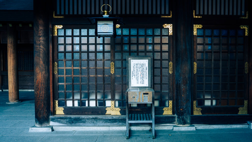 Wooden offering box in front of a glass and wood screen at Hokkaido-Jingu