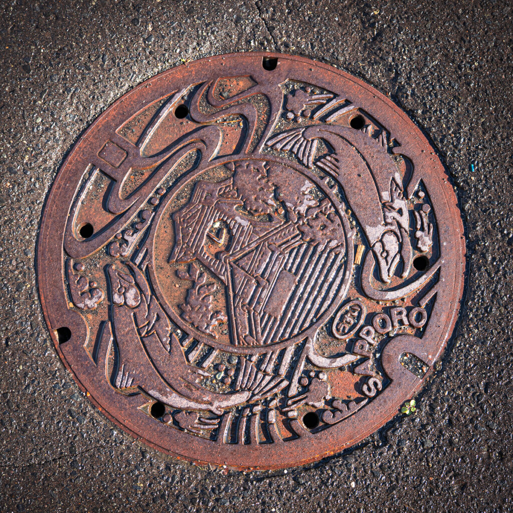 Decorative Sapporo manhole cover with the clock tower and salmon design.