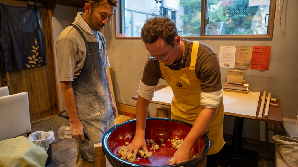 Instructor Taku-san watches Mac mix buckwheat flour and water in a large red bowl at a soba-making class in Sapporo.