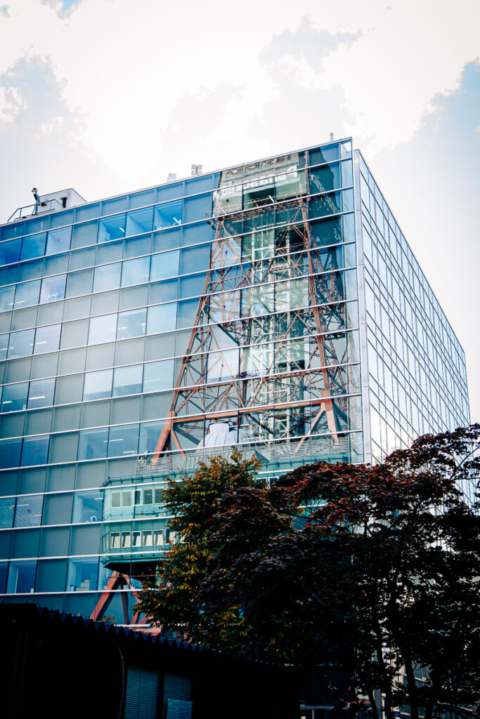 Reflection of Sapporo TV Tower in mirrored glass of a modern building.