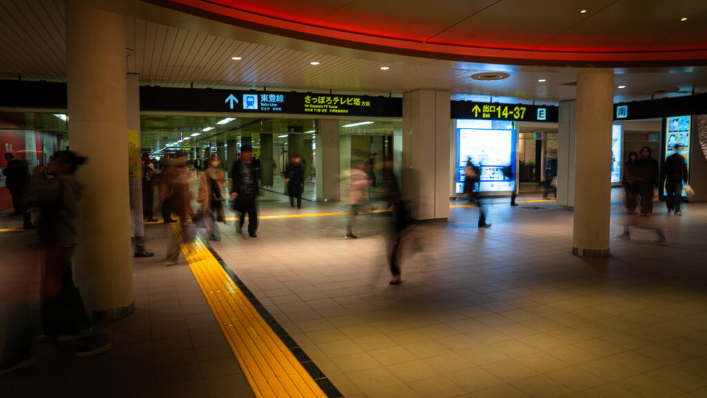People walk through Sapporo’s bright underground shopping walkway with directional signs.