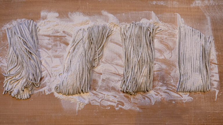 Overhead shot of neatly arranged soba noodles before cooking.