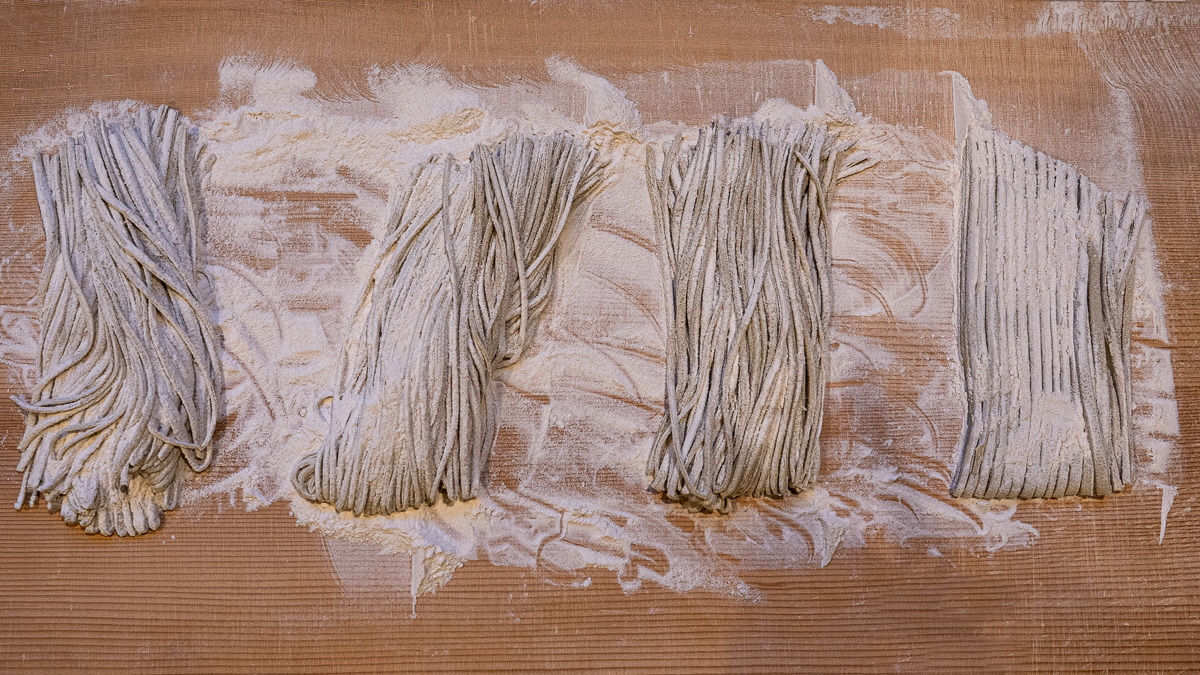Overhead shot of neatly arranged soba noodles before cooking.