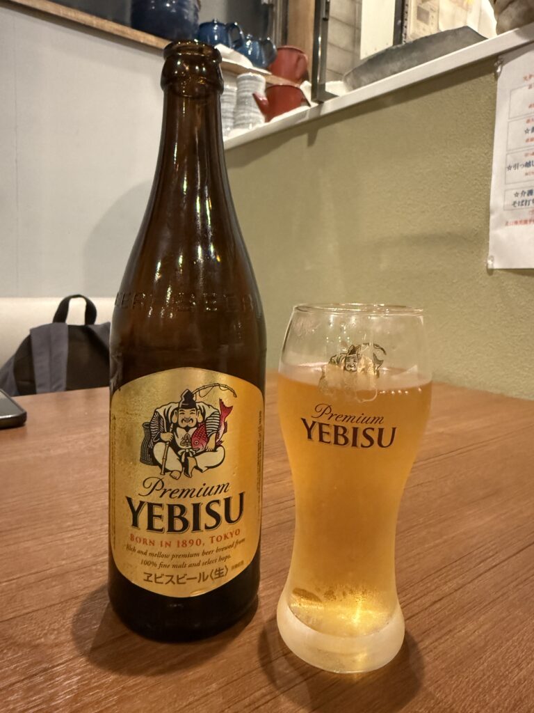 Close-up of a cold Yebisu beer bottle and filled glass on the restaurant table.