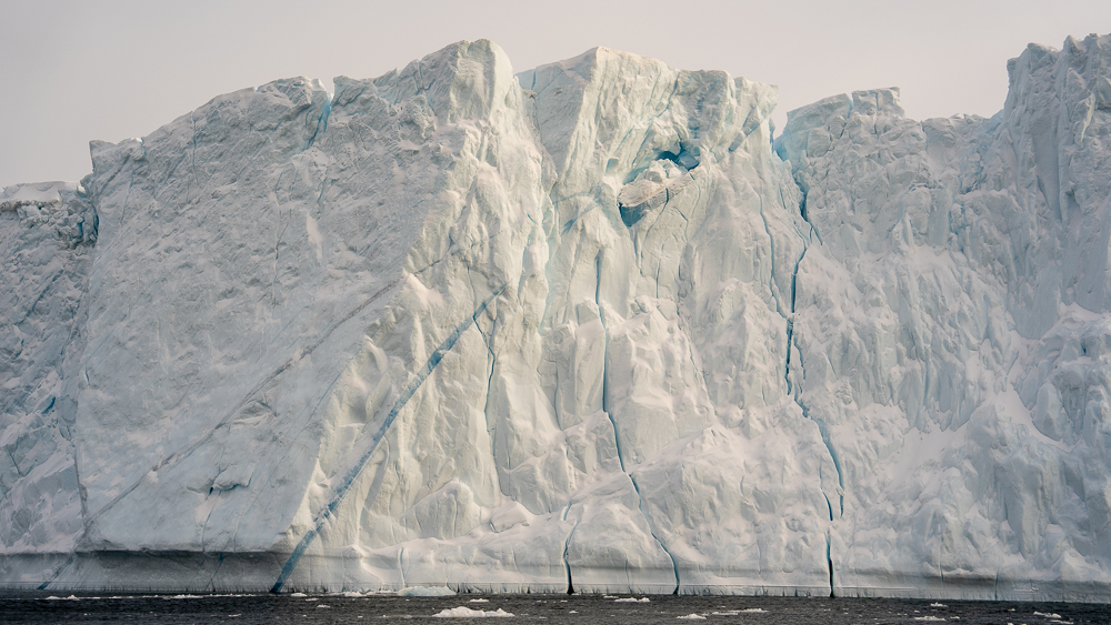 Large iceberg marked by a vivid blue stripe and vertical cracks in Disko Bay.