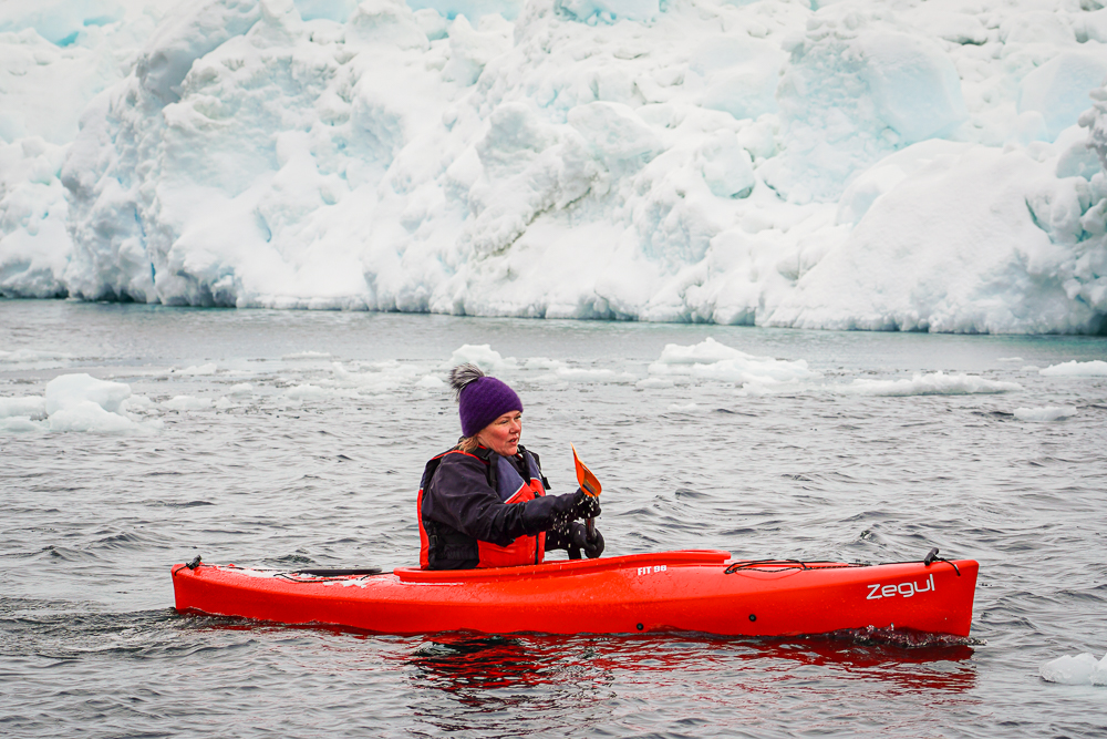 Laurie Forrest Moy paddling slightly toward the camera among icebergs in Disko Bay.