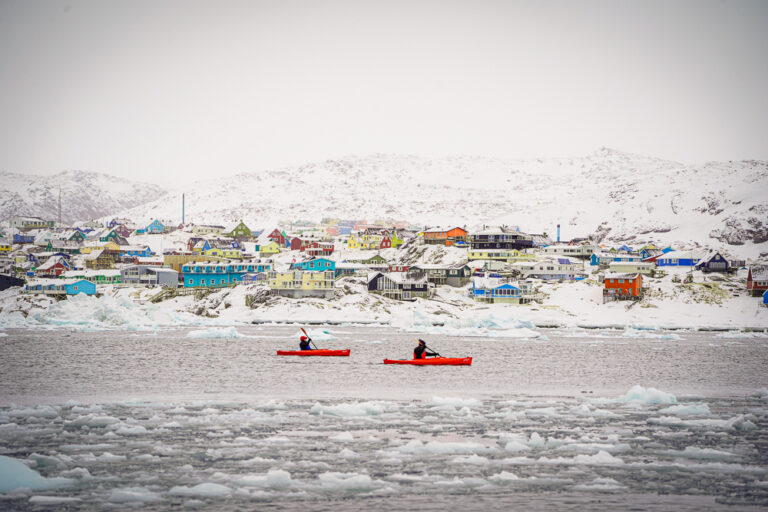 Kayakers paddling near Ilulissat as light snow falls over Disko Bay.