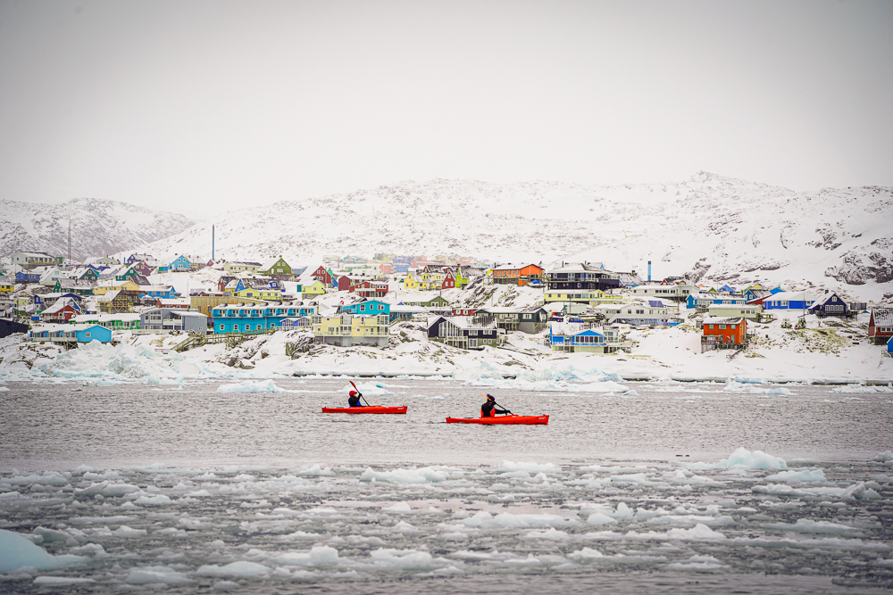 Kayakers paddling near Ilulissat as light snow falls over Disko Bay.