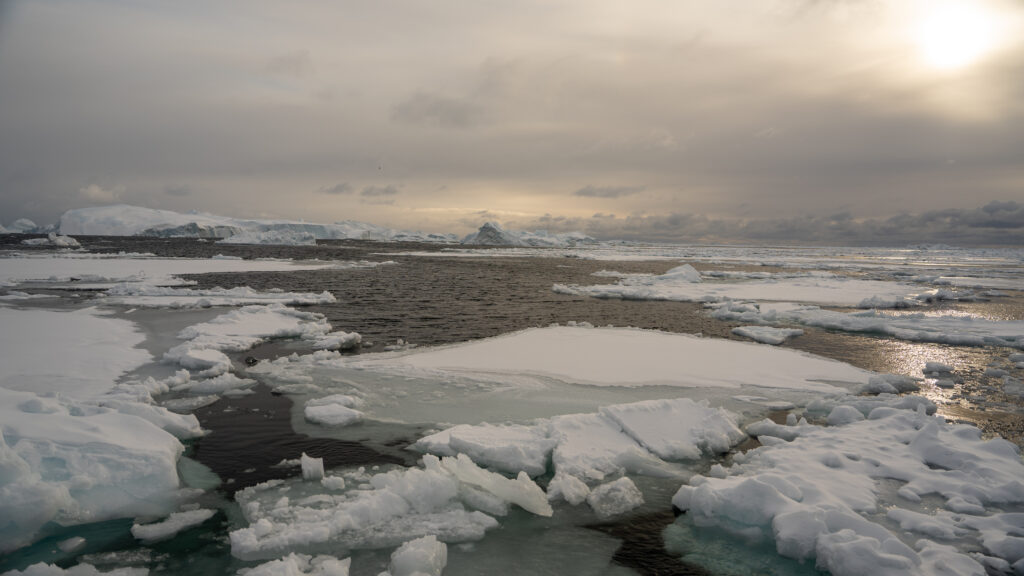Flat sea ice covering Disko Bay near Ilulissat, Greenland, as the Arctic sun getting low in the sky.