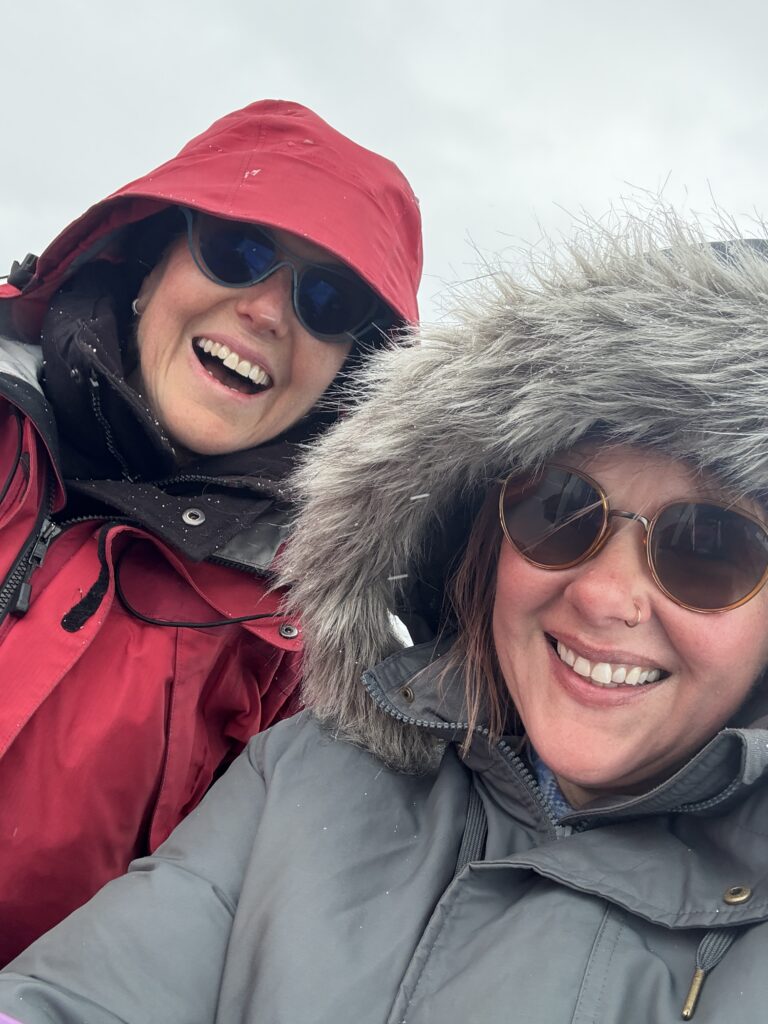 Two travelers bundled in winter clothing aboard a boat in Disko Bay before a kayaking tour.