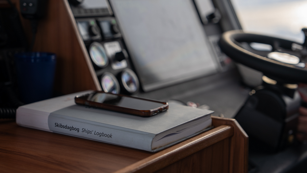 Cell phone resting on a hardback ship's logbook aboard a boat in Greenland.