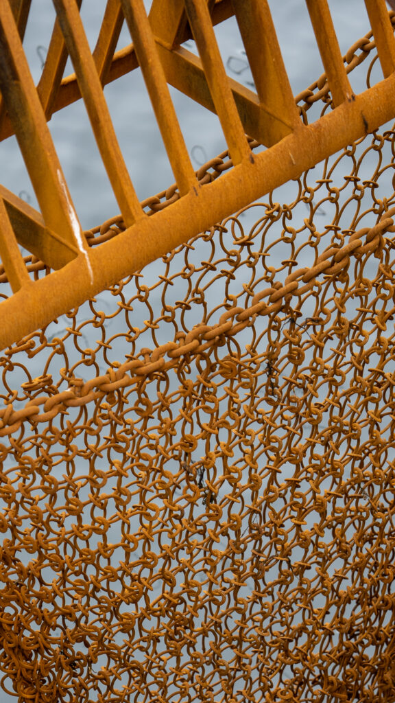 Close-up of mustard yellow metal mesh forming a repeating geometric pattern.