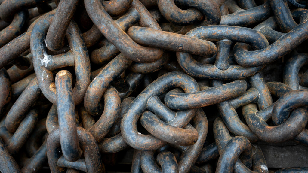 Close-up of heavy rusted steel chains piled together on a dock in Nuuk Harbor.