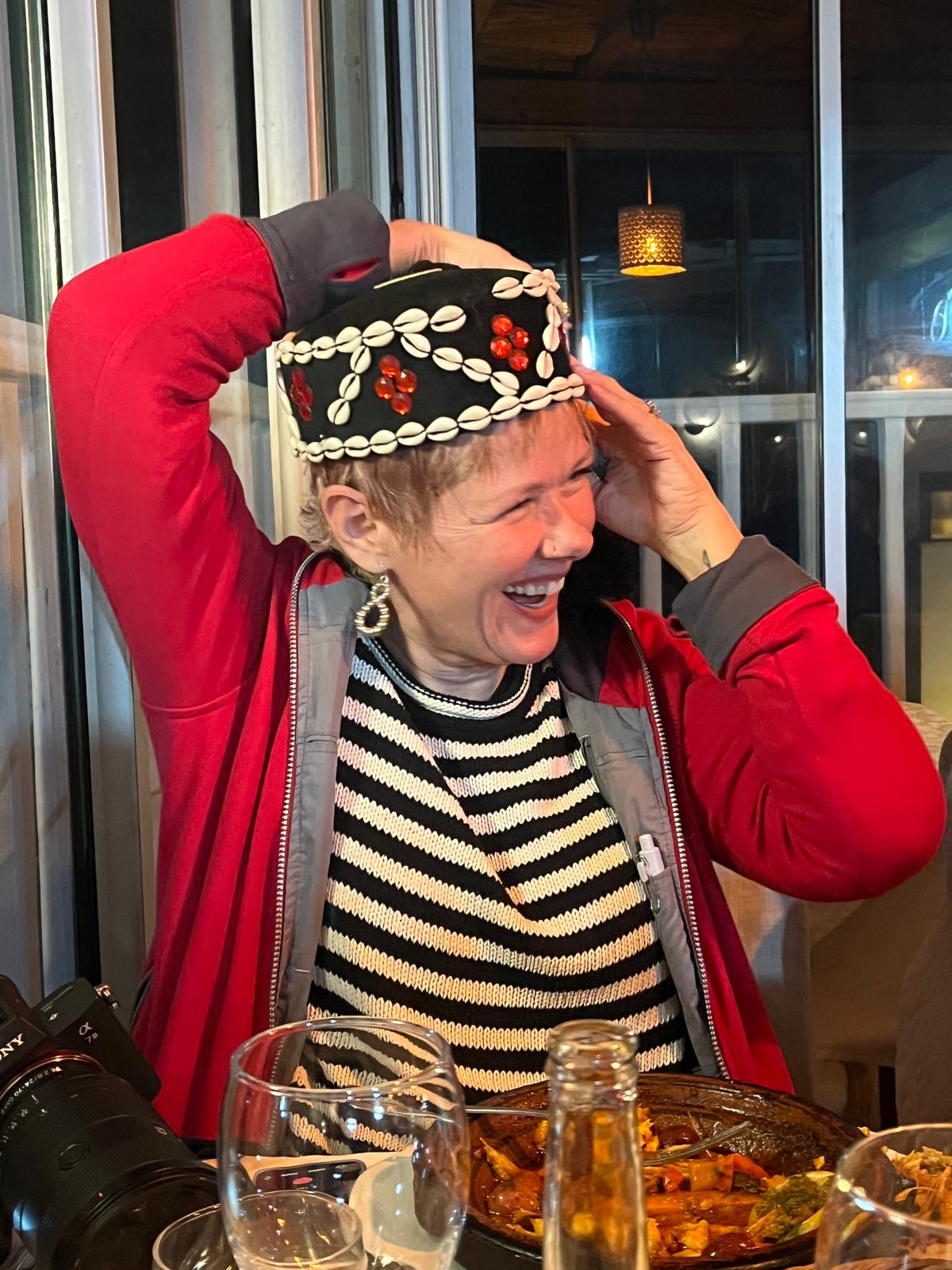 woman laughing while trying on traditional cap in Morocco
