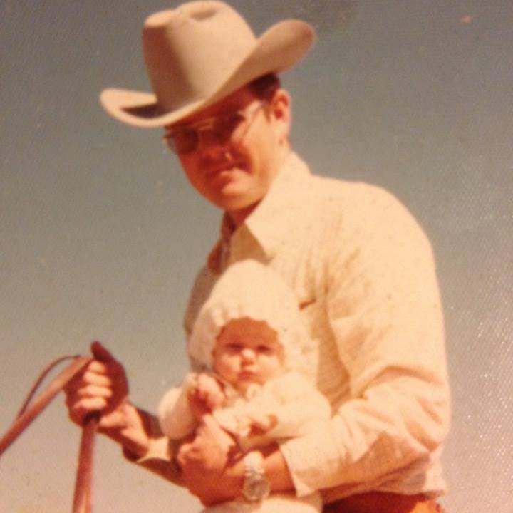 old photograph of cowboy with a white hat, sitting on a horse and holding a baby