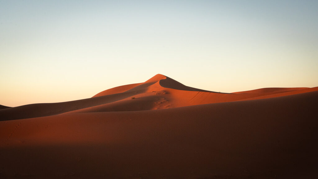 Distant dune with a pointed peak and a ridgeline snaking in from the right near Erg Chigaga, Morocco.