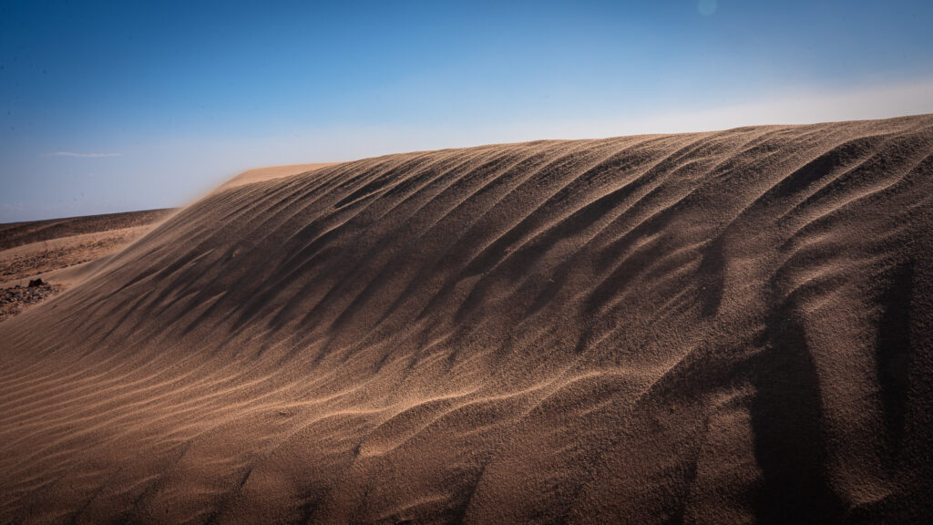 Wide view of a small dune showing sand shaped by winds blowing from multiple directions near Erg Chigaga.
