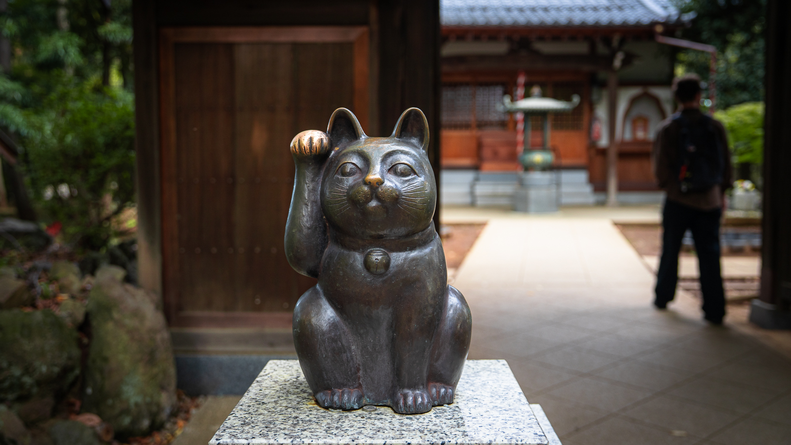 Bronze maneki-neko statue with worn nose and raised paw from repeated touch.