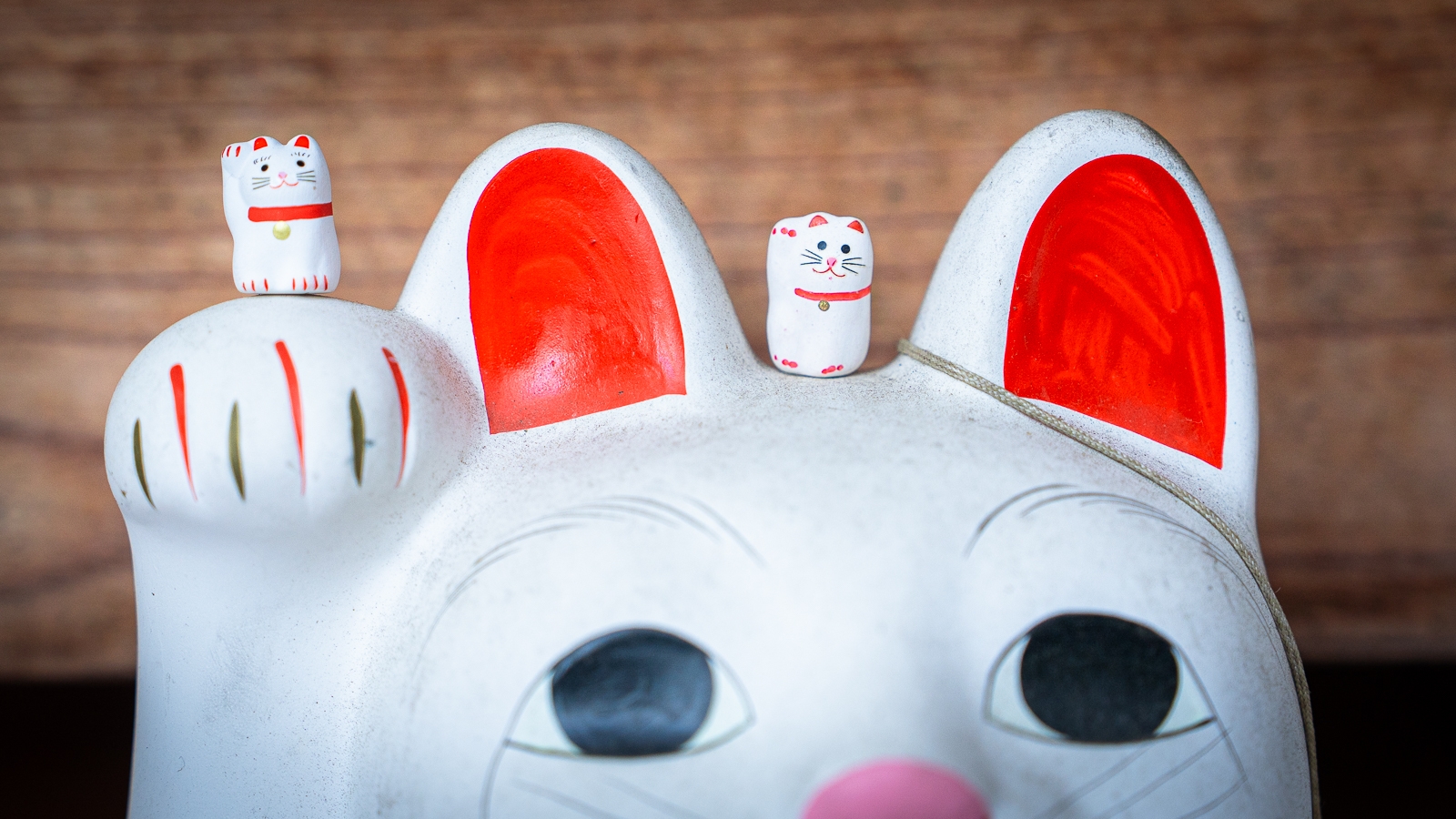 Large lucky cat statue with two smaller cats placed on its head and paw.