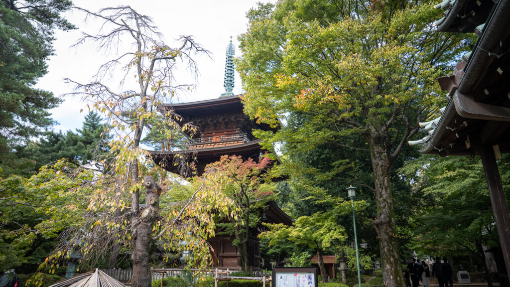 View of Gotokuji’s pagoda spire framed by dense green leaves.