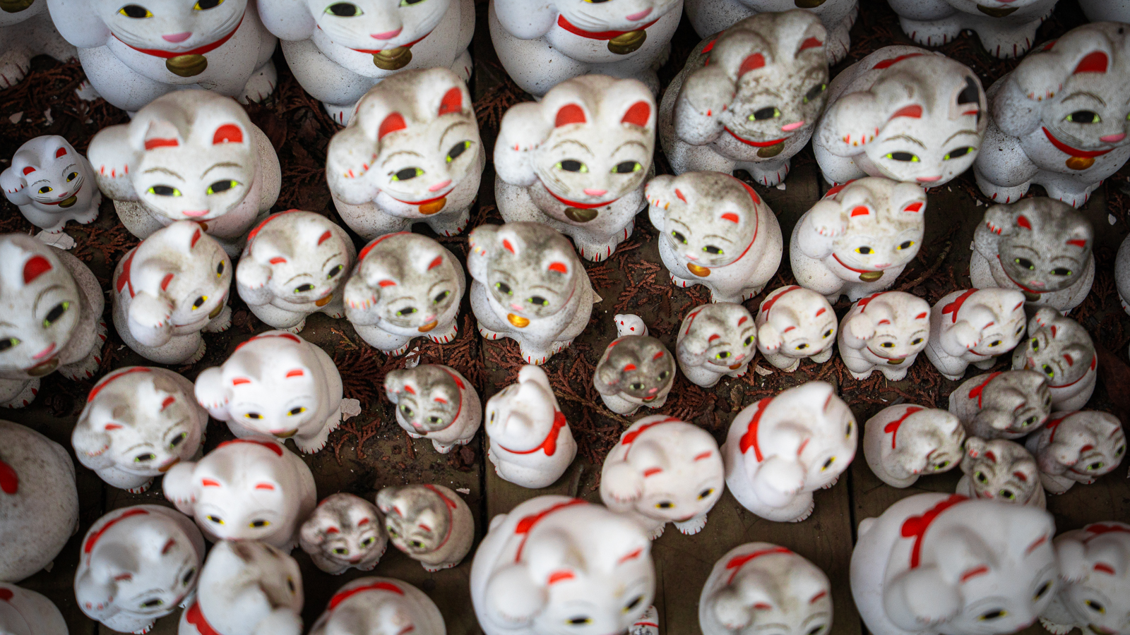 Weathered and dirty lucky cats indicating long-term placement outdoors.