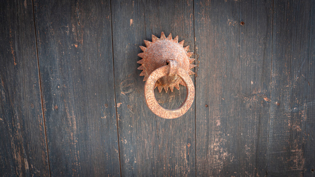 Weathered metal door handle on a dark green wooden door at Auberge Kasbah Touareg in M’Hamid.