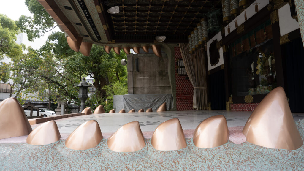 View past the lion’s teeth toward the stage area used for shrine ceremonies.