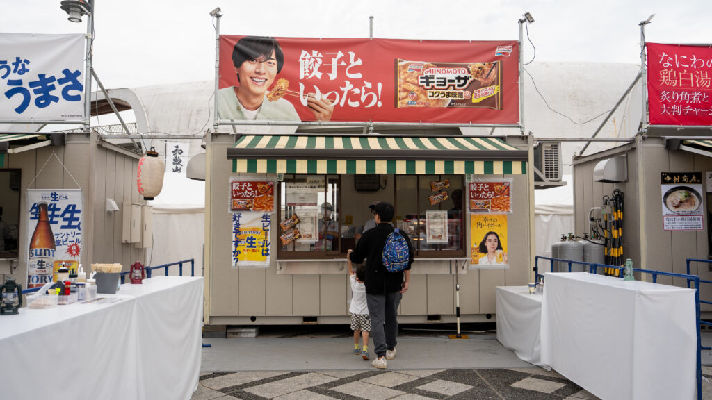A man and child study the menu at a gyoza booth during Tokyo Ramen Festa.