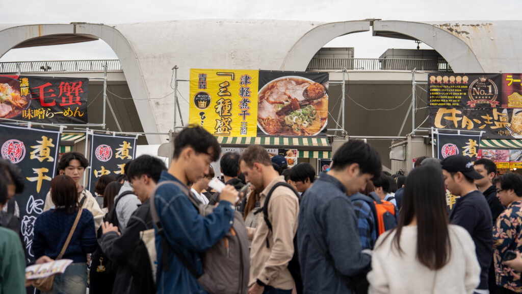 Crowd gathers around a booth serving Tsugaru dried sardine ramen.