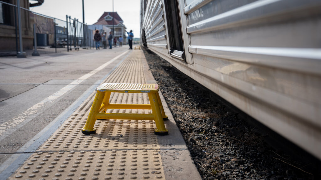 Yellow step stool on the platform with a porter standing in the background.