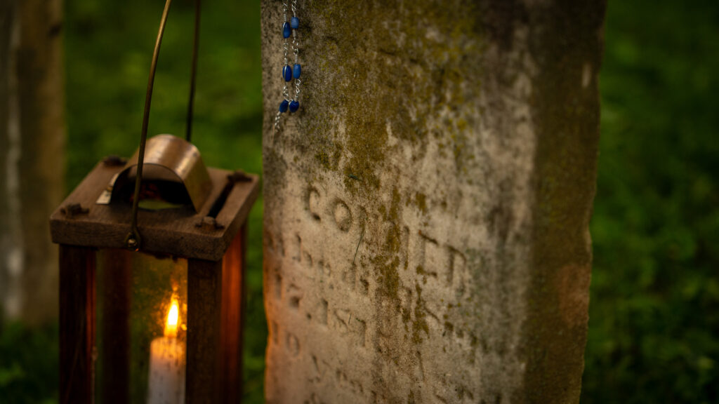 A lantern glows beside the weathered headstone of Conner, a 10-year-old child buried in a Shepherdstown cemetery.