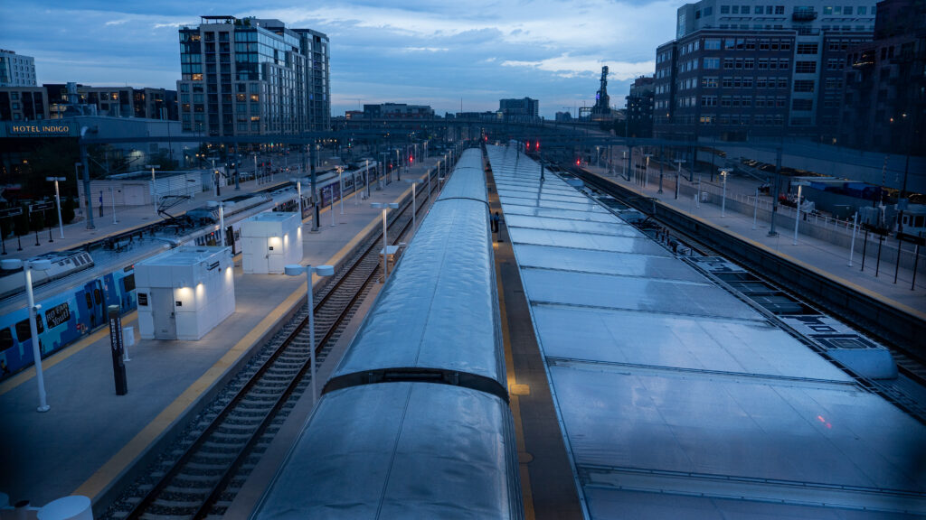 Overhead view from a pedestrian bridge showing the top of the train and Denver’s station area.