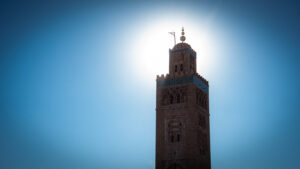 Silhouette of the Koutoubia Mosque minaret in Marrakesh against a bright winter afternoon sky near Jemaa el-Fnaa.
