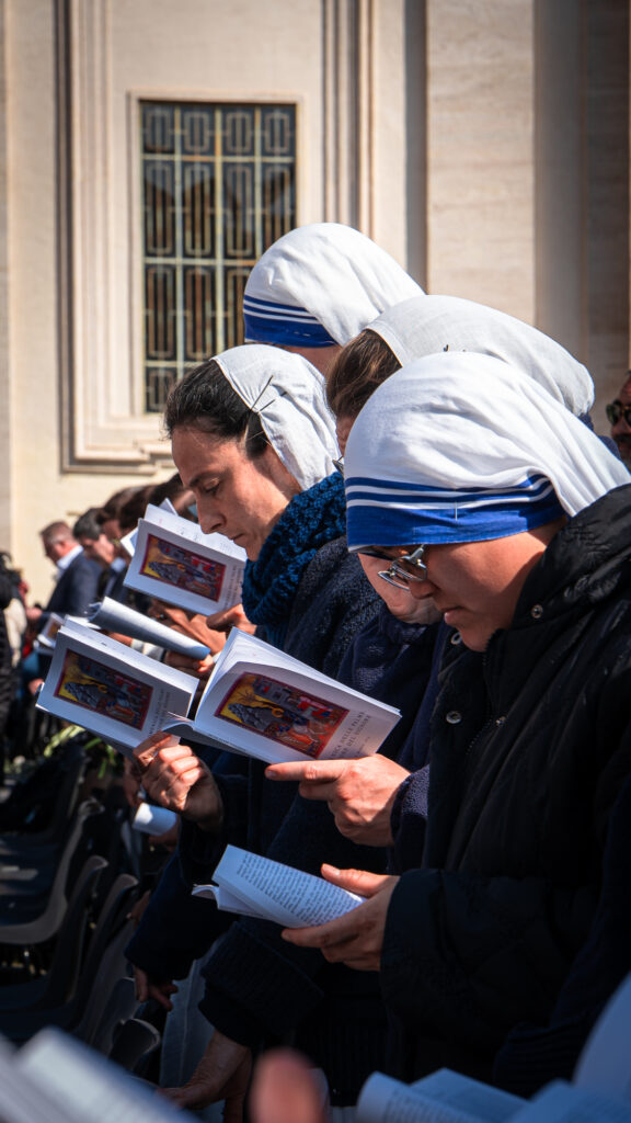 Row of nuns in blue and white habits reading missalettes in St Peter’s Square