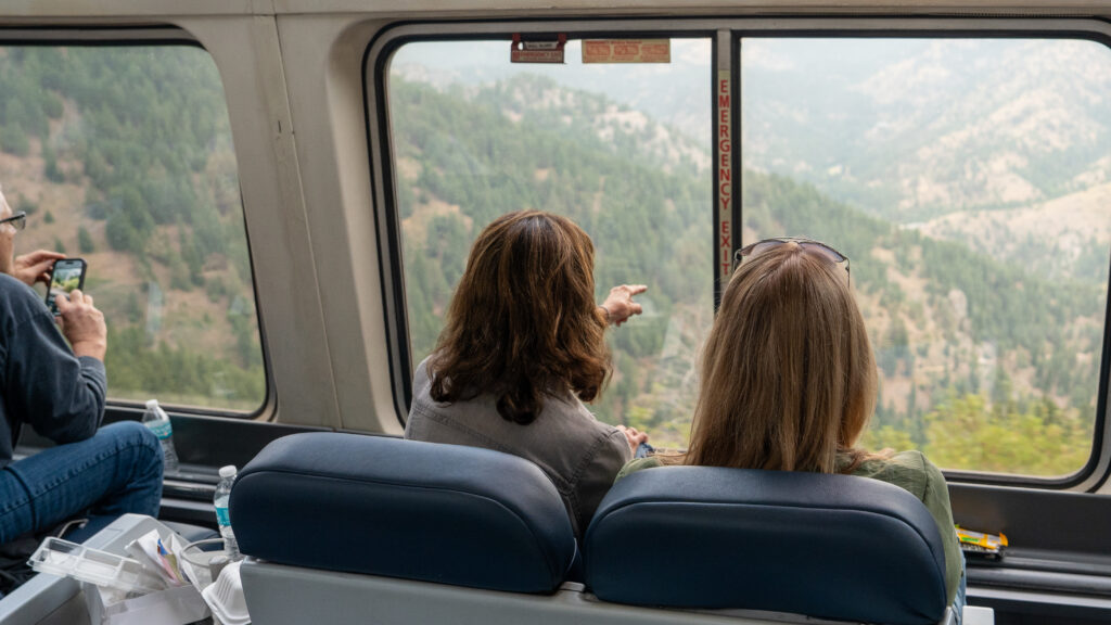 Passengers in the observation car pointing toward views of mountain scenery.