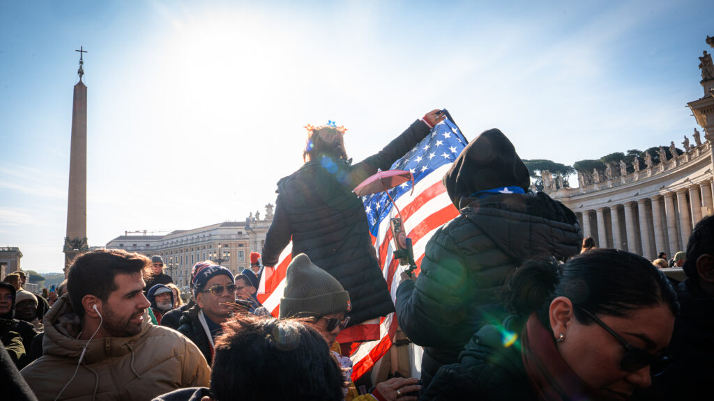 Couple dressed in American flag clothing posing with US flag in St Peter’s Square