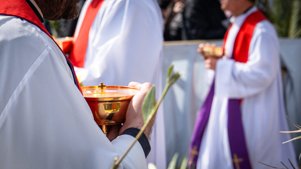 Priest holding ciborium preparing to distribute Eucharist during Palm Sunday Mass