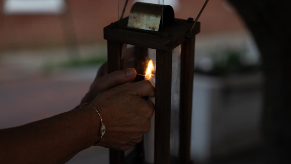Close-up of Janet Hughes lighting a candle inside a handheld lantern before a Shepherdstown Mystery Walk.