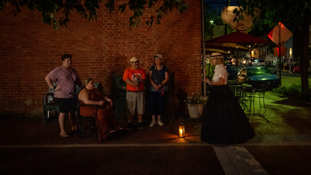Janet Hughes speaks with guests outside the Shepherdstown Sweet Shop at the end of an evening historical ghost walk.