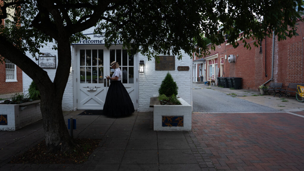 Janet Hughes of Shepherdstown Mystery Walks stands beside the old public library in historic Shepherdstown, West Virginia.