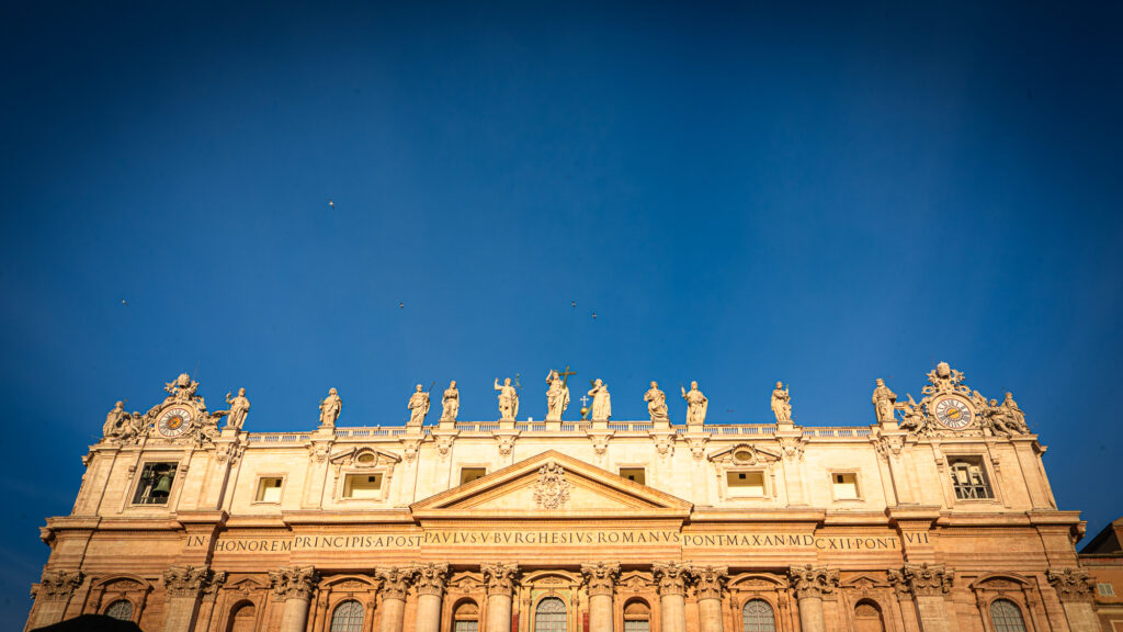 Warm sunrise light illuminating facade of St Peter’s Basilica in Vatican City