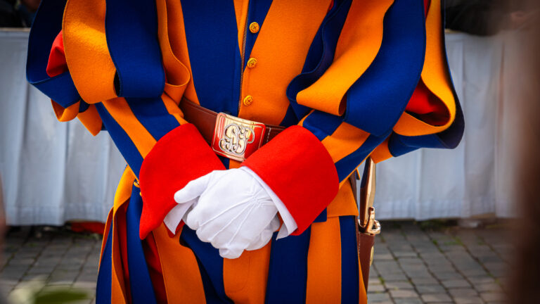 Close-up of Swiss Guard uniform with blue yellow stripes white gloves and gold belt