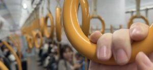 close up on a hand on a yellow train handle,a row of handles disappear into the background